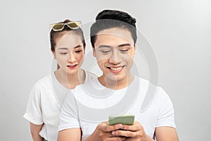 Photo of couple with her looking into her guy screen and him cheating to his lover smiling toothily isolated over white background