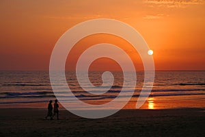 Photo of a couple strolling on the beach on a summer evening photo