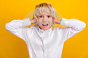 Photo of crazy amazed speechless schoolboy hands cover ears wear school uniform isolated yellow color background