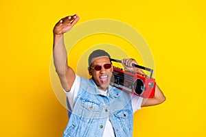 Photo of crazy funky guy dressed jeans waistcoat arm up enjoy music boombox on shoulder isolated on vibrant yellow color