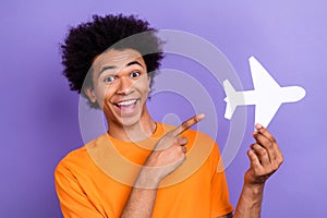 Photo of crazy funky young tourist guy directing forefinger demonstrate boeing airplane paper model isolated on purple