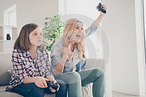 Photo of crazy funny blond lady yelling mom daughter sit sofa hold joystick play video game winner loser stay home