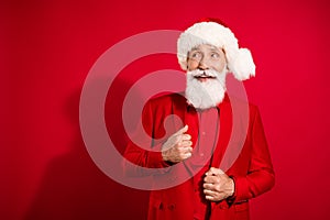 Photo of curious excited successful santa claus look empty space wear x-mas hat suit on red color background