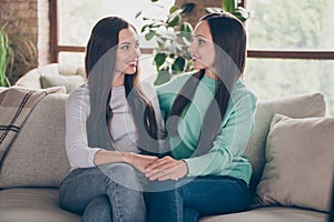 Photo of curious positive two ladies sit divan hold hands wear casual outfit in comfortable home indoors