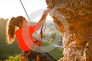 Photo of curly-haired female tourist clambering over rock