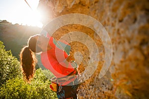 Photo of curly-haired female tourist clambering over rock