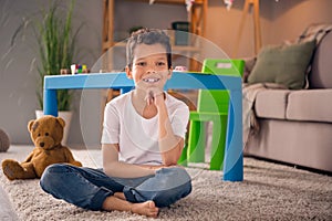 Photo of cute adorable preschool boy sitting floor in nursery room playing with many toys comfort domestic house