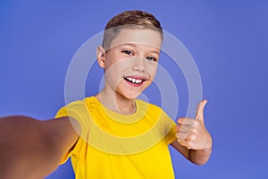 Photo of cute beautiful child boy wear trendy yellow clothes make selfie thumb up cool offer isolated on purple color