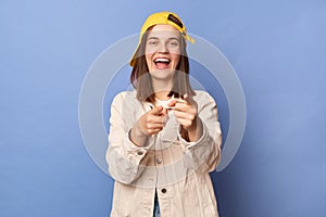 Photo of cute charming positive brown haired teenager girl wearing baseball cap and jacket posing isolated over blue background,