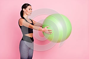 Photo of cute charming young lady sportswear rising big green fit ball smiling isolated pink color background