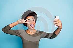 Photo of cute cheerful nice attractive black skinned woman fooling before camera showing v-sign sticking out wearing