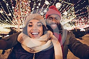 Photo of cute excited boyfriend girlfriend dressed winter season outfits recording video x-mas fair outdoors urban city