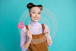 Photo of cute excited toothy two buns hairstyle lady hand hold sugary delicious colorful heart shaped stick caramel wear