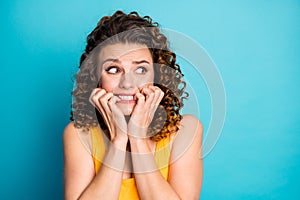 Photo of cute neurotic redhead girl biting nails look side empty space horrified wear yellow tank-top isolated blue