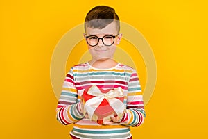 Photo of cute positive boy wear bright clothes hold receive gift hold heart shape box isolated on yellow color