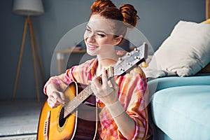 Photo of cute positive girl toothy smile good mood enjoy playing guitar free time chill apartment inside