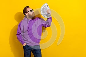 Photo of cute pretty guy dressed purple sweater dark eyewear holding money fan empty space isolated yellow color