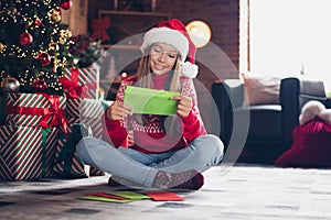 Photo of cute pretty little lady dressed red print pullover reading x-mas christmas greetings indoors home room