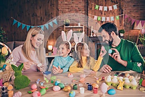 Photo of cute smiling family prepare spring holiday paint easter eggs mom and dad help their kids hobby spend free time