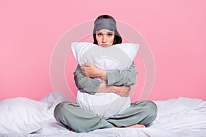 Photo of cute upset young lady sleepwear sitting blanket embracing pillow isolated pastel pink color background
