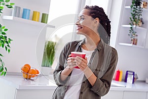Photo of cute young female look window enjoying tasty morning cup of latte in her new modern apartment kitchen room