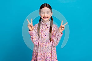 Photo of cute young girl show double v sign everyone unknown person wear dress first day kindergarten isolated on blue