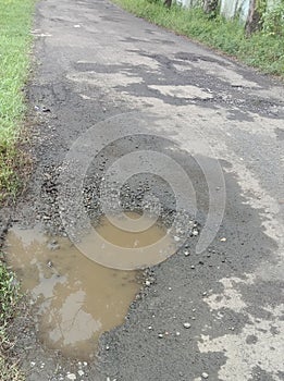 Photo of damaged and watery asphalt road