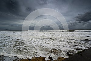 Photo of dark clouds over Sunshine Coast with foamy and rocky shore in Queensland, Australia