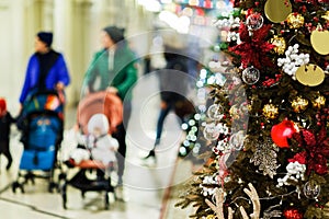 Photo of decorated spruce in store on background of moms with strollers