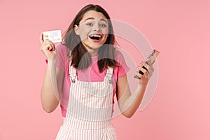 Photo of delighted charming girl holding cellphone and credit card
