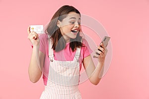 Photo of delighted charming girl holding cellphone and credit card