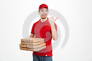Photo of delivery dealer 25y in red uniform carrying stack of pi
