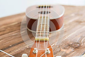 Photo depicts musical instrument ukulele guitar on a wooden table