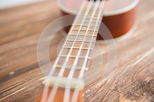 Photo depicts musical instrument ukulele guitar on a wooden table