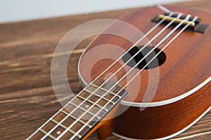 Photo depicts musical instrument ukulele guitar on a wooden table