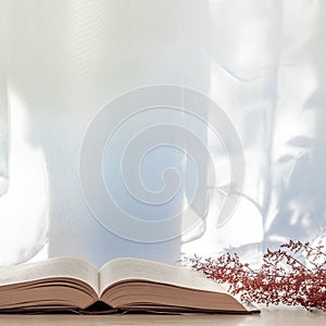 Photo of a desk with an open book and dried red grass