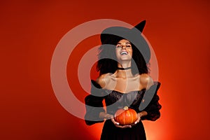 Photo of diabolic dangerous dark witch lady hold magical mystical pumpkin for summon creepy demon over red background