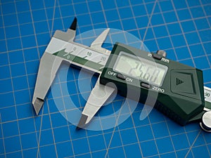 Photo of a digital vernier caliper with centimeters and millimeters on a blue background cutting mat