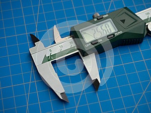 Photo of a digital vernier caliper with centimeters and millimeters on a blue background cutting mat photo