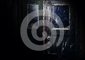 Photo of dirty abandoned obsolete door with scary ghost face