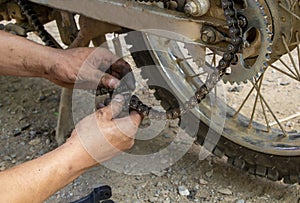 Photo of dirty mechanic`s hands holding a broken motorcycle chain for repairing