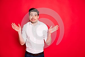 Photo of disinterested man showing his palms grimacing misunderstanding while isolated with red background