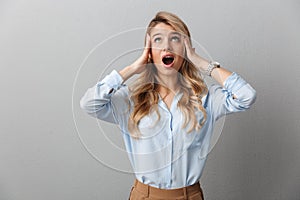 Photo of displeased blond businesswoman with long curly hair screaming and grabbing her head