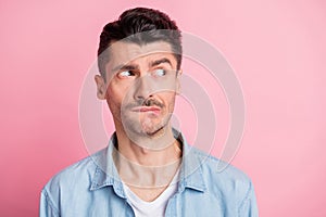 Photo of displeased brunette young man look empty space bite teeth lips isolated on pastel pink color background