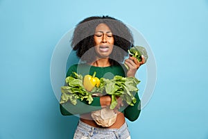 Z nespokojný a nešťastný žena kučeravý vlasy predstavuje potraviny a čerstvý zelenina plače cez brokolica 