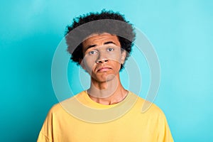 Photo of dissatisfied disappointed guy with afro hairdo dressed yellow t-shirt make sad face isolated on turquoise color