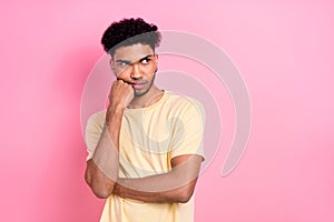 Photo of dissatisfied man with afro hairstyle wear yellow t-shirt look empty space hand on cheekbone isolated on pink