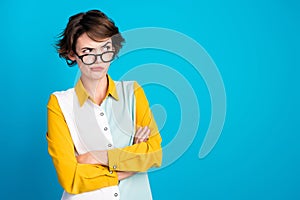 Photo of distrustful girl with crossed hands look on empty space isolated blue color background