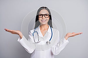 Photo of doctor lady palms hold empty space wear stethoscope spectacles white uniform isolated grey color background