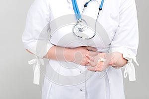 Photo of doctor showing on drugs in hands and gripes on light background